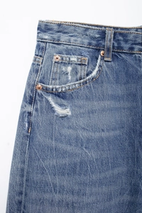 Detail of blue denim waistband showing worn accents and vintage brass rivets