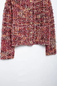 Detailed close-up of red tweed cardigan showing colorful textures and golden buttons