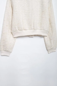 Détail de veste en tweed crème montrant le col côtelé et la texture du tissu tissé