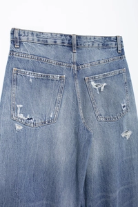 Close-up of distressed light blue denim jeans showing back pocket details and ripped textures