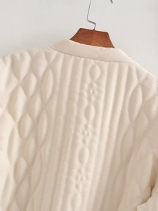 Detail of premium beige quilted texture with intricate embroidery on winter jacket back