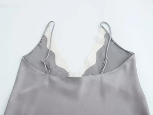 Detail shot of grey satin camisole featuring delicate white floral lace trim on V-neckline