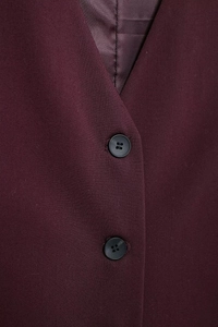Détail de la veste bordeaux montrant la texture du tissu et les boutons noirs