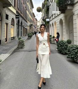 Detailed layered look of white knit vest with golden buttons and pleated midi skirt set