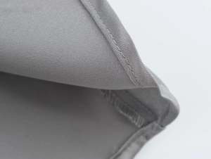 Close-up of grey satin fabric texture with neat stitching and diagonal twill pattern