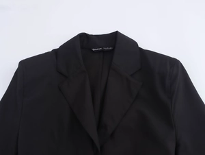 Detail of black shirt dress collar showing garment labels and premium fabric texture