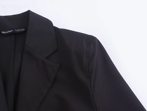 Detailed close-up of notched lapel and branded inner tag on black shirt dress