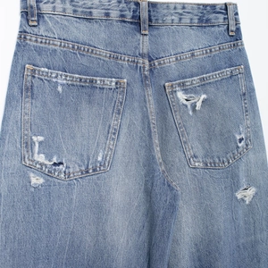 Relaxed fit light blue distressed jeans for women featuring stylish ripped hole details