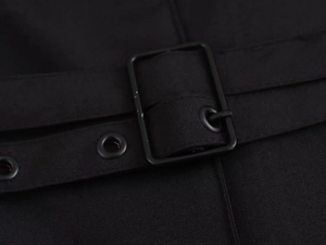 Detail of a black woven belt with a metal pin buckle and eyelets for the dress