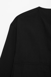 Détail du tissu en coton noir montrant le col rond et l'épaule tombante avec couture propre