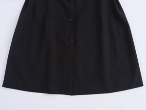 Detailed close-up of vertical black buttons and clean hem on shirt dress
