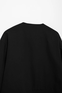 Détail des coutures d'épaule et de l'encolure sur une veste noire à manches longues