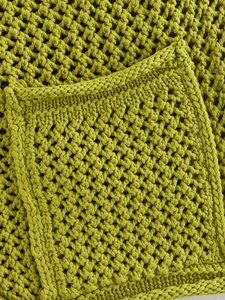 Primer plano de chaleco de punto verde brillante con textura calada y detalle de bolsillo