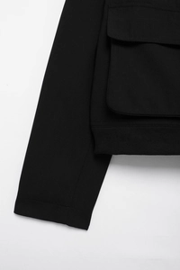 Vue détaillée d'une veste noire avec poche à rabat utilitaire et ourlet en tricot côtelé