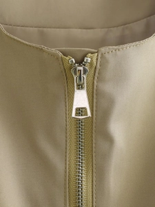 Dettaglio macro della cerniera in metallo argento su gilet in twill color kaki