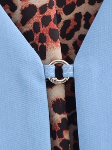 Detail of blue twill denim vest featuring a silver metal ring and leopard print lining