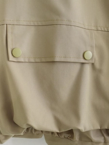 Dettaglio macro della tasca kaki con bottoni verde oliva e trama in twill denim