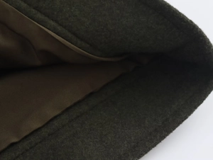 Gros plan détaillé du tissu en laine olive foncé avec doublure en soie marron et couture