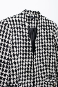 Close-up of black and white houndstooth tweed jacket with refined woven texture and lining