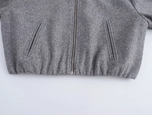 Dettaglio dell'orlo della giacca di lana grigia con zip in metallo e bordo elastico