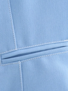 Detailed close-up of light blue denim vest with white contrast stitching on pockets