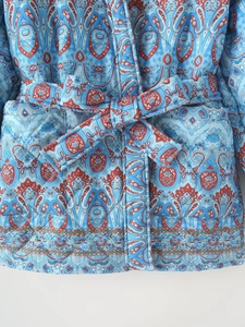 Détail de la veste matelassée bleu clair à motif paisley et ceinture nouée assortie