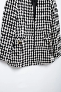 Close-up of houndstooth wool jacket texture with golden buttons and black silk lining