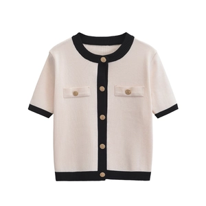 Detail of short sleeve knit top with gold metal buttons and black contrast trim
