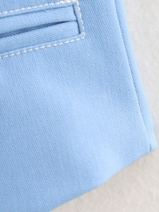 Close-up of light blue denim vest with white contrast stitching and twill texture detail