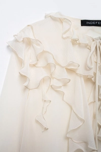 Detail shot of elegant cream chiffon blouse featuring layered ruffle decorative trim