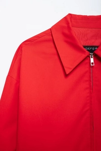 Detail of red zip-up jacket collar with silver metal zipper and fabric texture