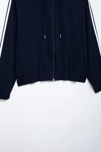 Detail of navy blue sports jacket showing side stripes, drawstring hood and zipper closure
