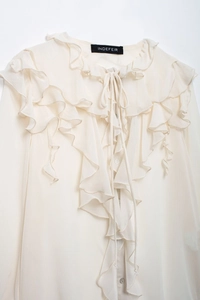 Detail of off-white chiffon blouse featuring layered ruffles and delicate V-neck tie