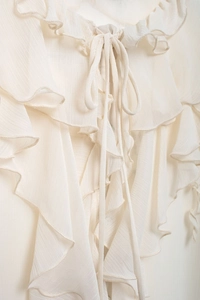 Close-up of elegant cream layered ruffles and delicate tie detail on a chiffon blouse
