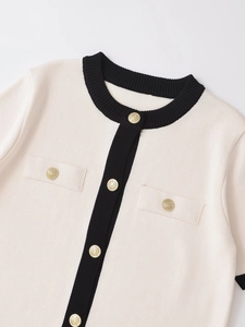 Close-up of contrast trim on white knit cardigan with golden lion head buttons