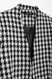 Close-up of black and white houndstooth wool blazer showing tweed texture and brand label