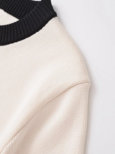 Detail of contrast rib knit neckline and drop shoulder seam on cream knitwear