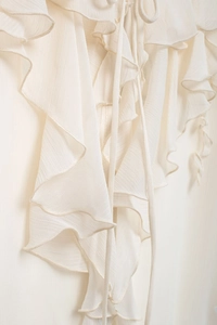 Detailed view of cream-colored tiered ruffles on a lightweight chiffon women's shirt
