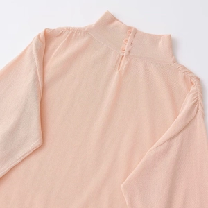 Haut en maille rose pêche pour femme avec col montant, détails de boutons et texture côtelée