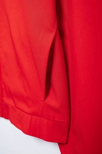 Detail of red twill jacket showing side pocket stitching and premium fabric texture