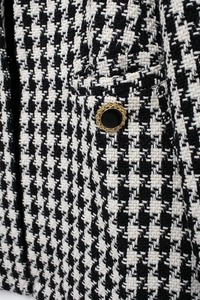 Macro shot of houndstooth tweed texture and vintage gold decorative button detail