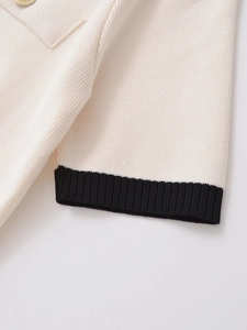 Detail of knit fabric with black ribbed cuff and gold embossed metal button
