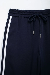Detail of navy blue joggers showing elastic waistband with metal tipped drawstring