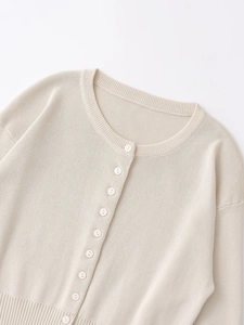 Detailed macro view of beige knit cardigan neckline with white buttons and ribbed finish