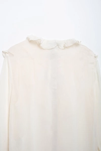 Detailed close-up of ivory chiffon fabric with elegant ruffle collar and ripple texture