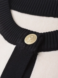 Macro shot of a luxury gold embossed button on a ribbed knit texture cardigan detail