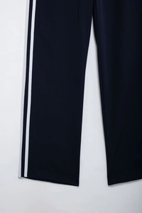 Detailed close-up of navy blue track pants with white side stripes and straight hem