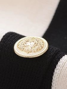 Detailed macro view of a vintage gold metal button on a black and white knit jacket