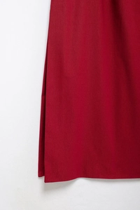Détail de l'ourlet de la robe midi rouge foncé montrant la texture et le drapé doux