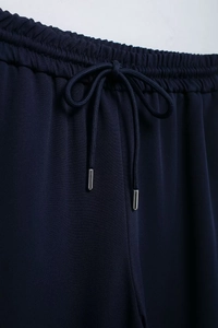 Detailed macro view of elastic waistband with adjustable drawstring on navy trousers